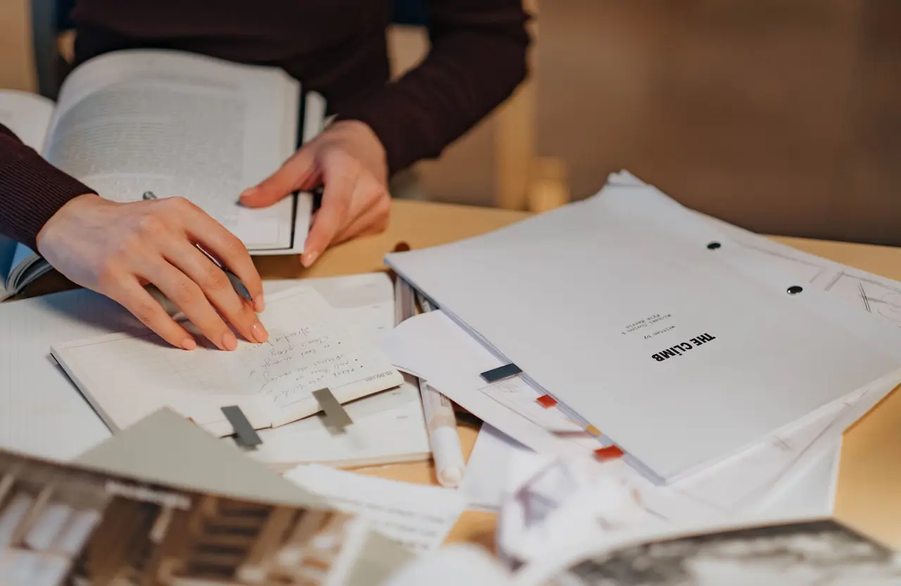 Hands writing notes in a notebook at a desk